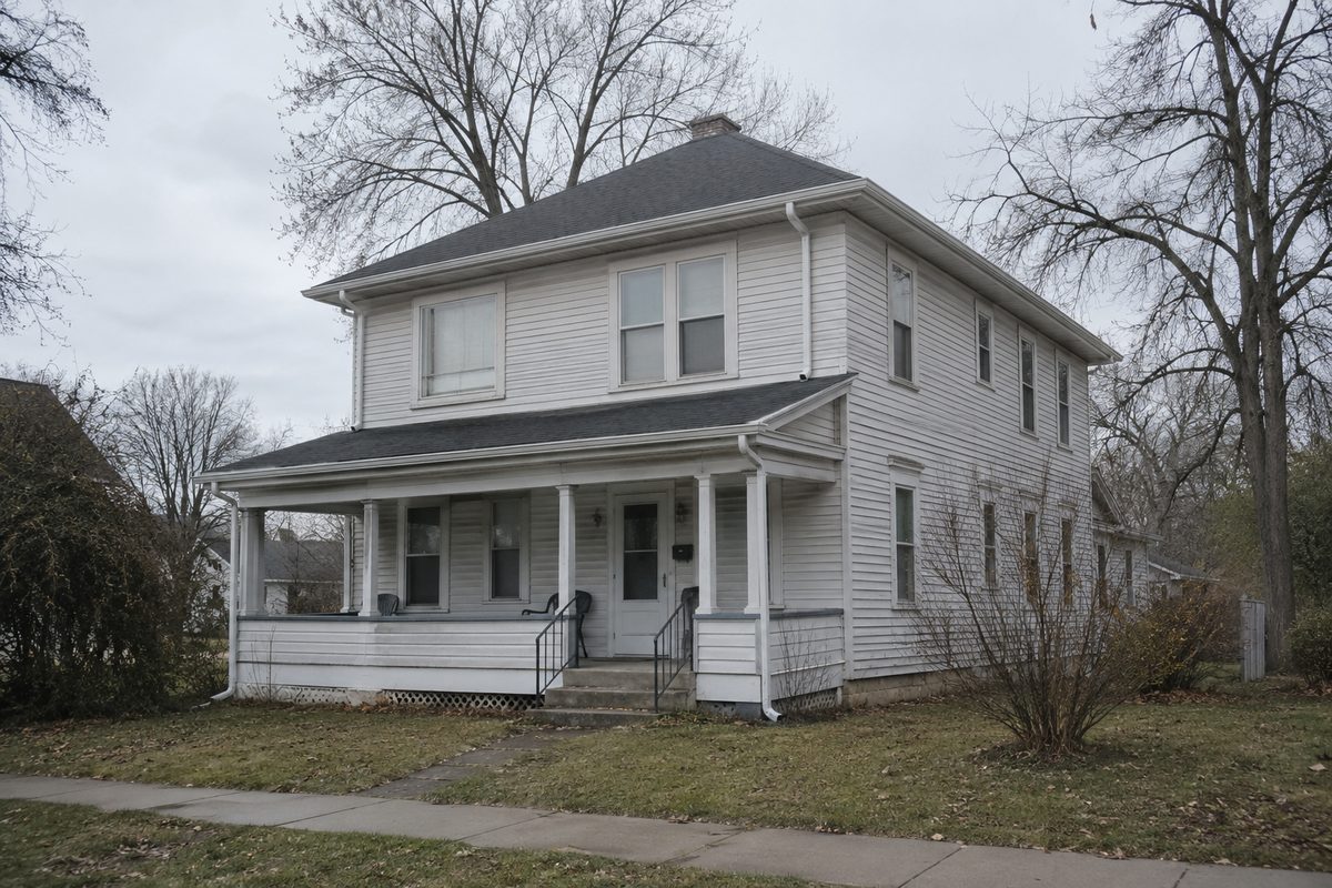 Older two-story wood-sided house with gutters along both roof levels